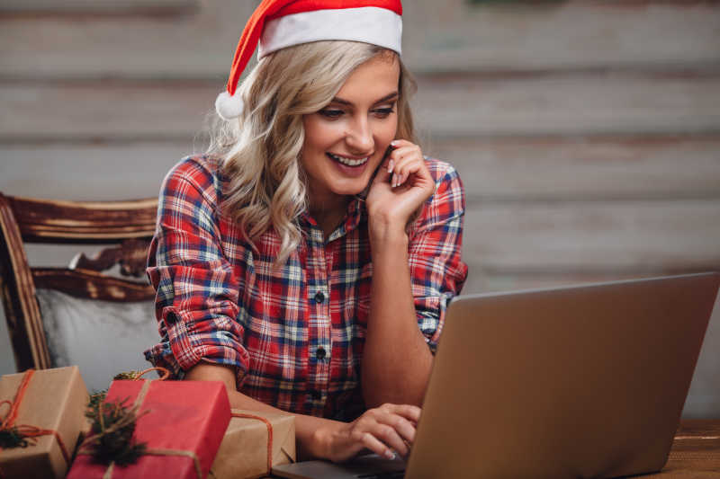 戴着圣诞帽的金发女人用笔记本电脑工作