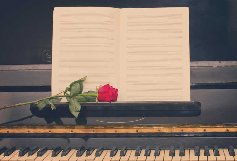 老式钢琴上的空白乐谱和红玫瑰
