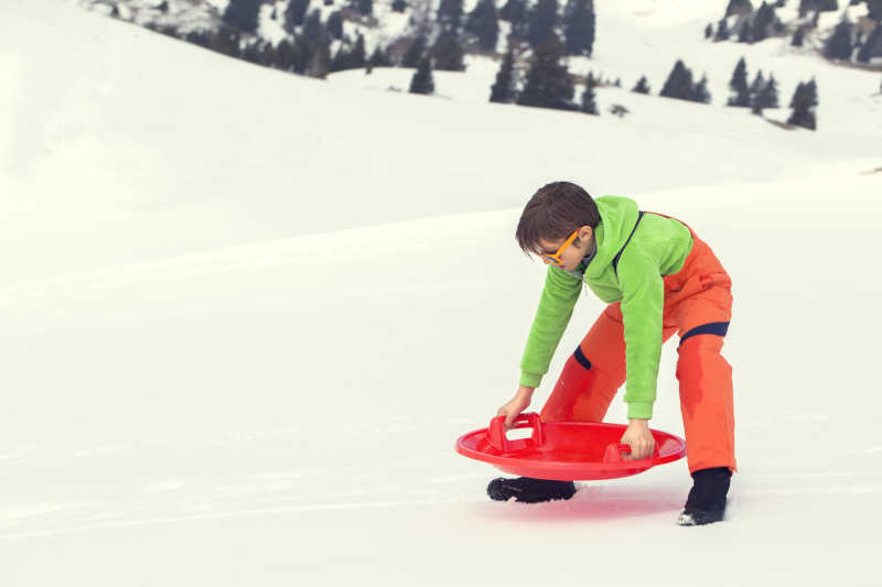 小男孩在雪地上搬动雪橇