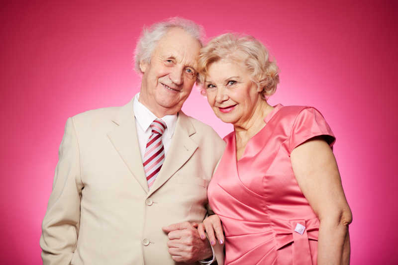 一对迷人的退休夫妇在粉红色背景下合影