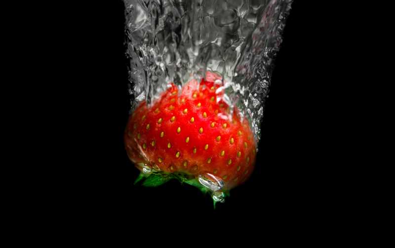 黑色背景中的水中草莓