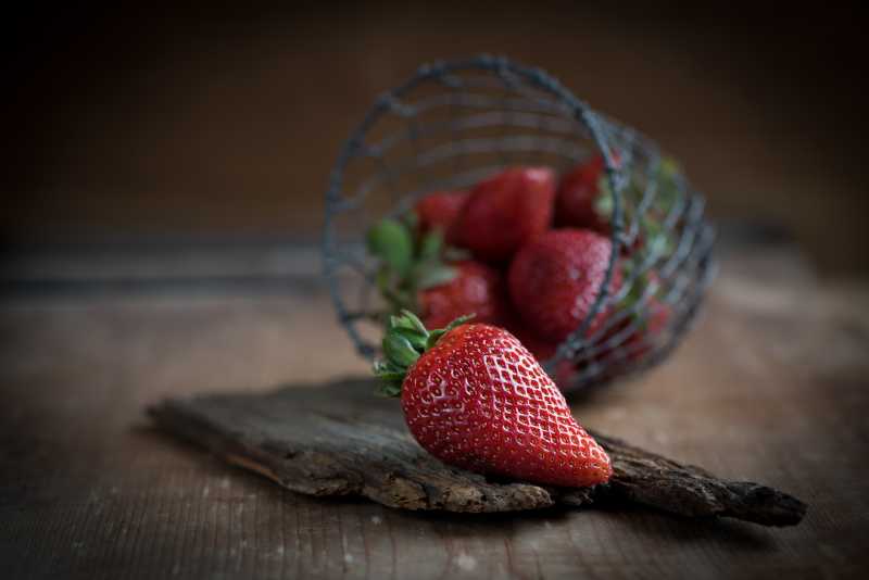 小框中掉落在木制板上的草莓