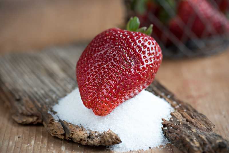 桌上的红色草莓和白糖