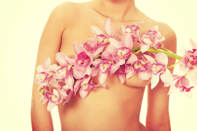 女人用粉红色的花覆盖乳房