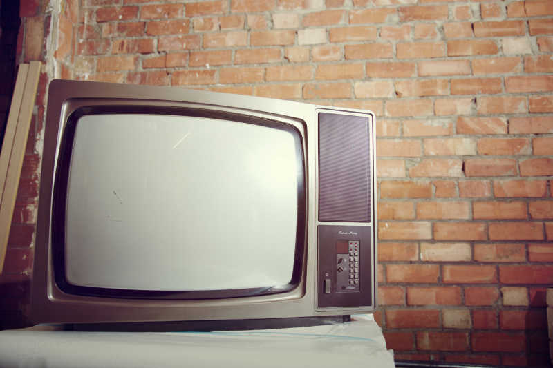 在砖仓库上的白色屏幕旧电视