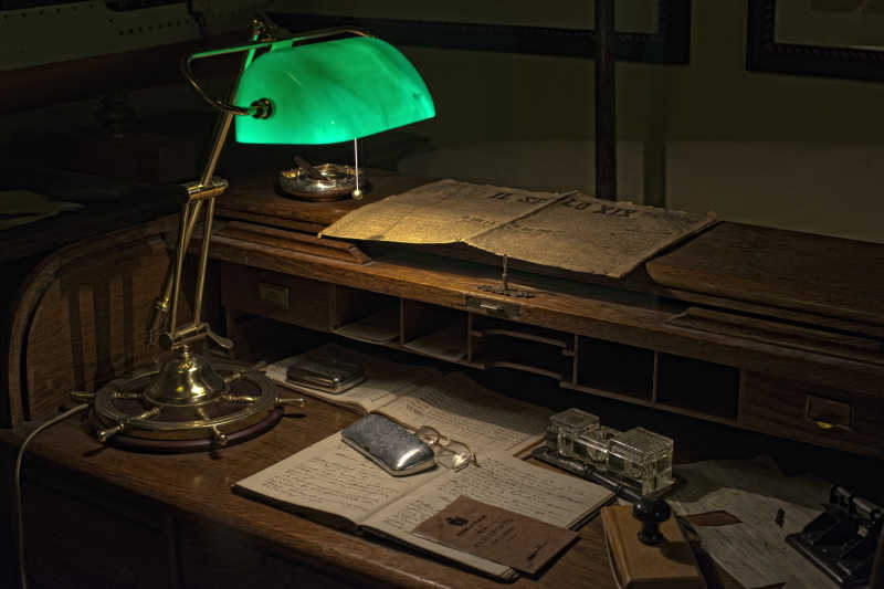 摆放着旧报纸和老式的旧台灯的复古的办公桌