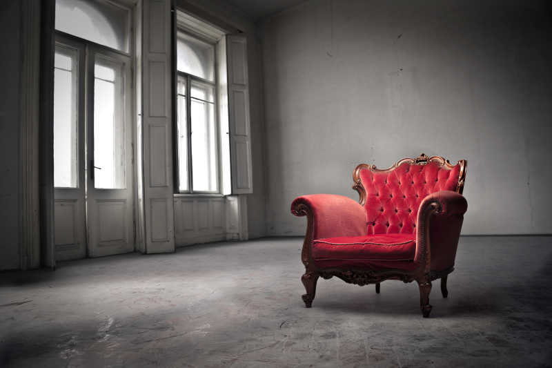 灰色老房子里的红色带扶手靠背的复古椅子