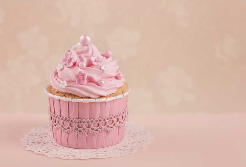 米色背景的粉红色纸杯蛋糕