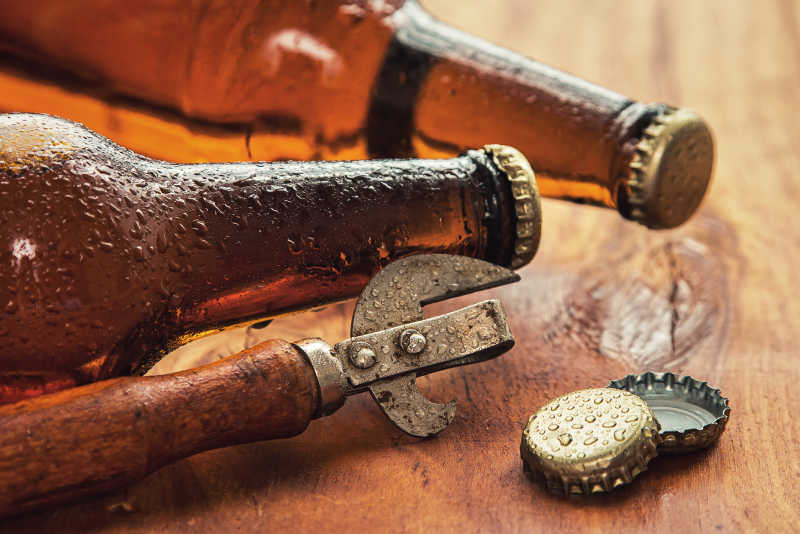 木质桌板上的葡萄酒开瓶器和啤酒