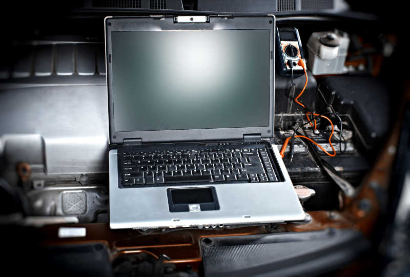 黑色笔记本电脑与汽车连接进行维修工作