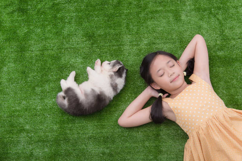 可爱的亚洲女孩和她的小狗在草地上睡觉