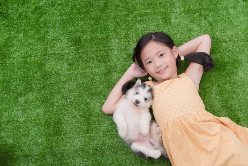 女孩和她的小狗躺在草地上