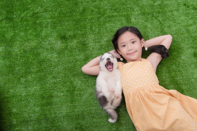 女孩开心地和她的小狗躺在草地上