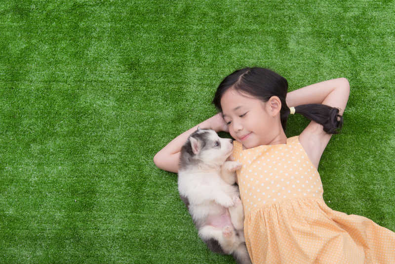 可爱的小女孩和小狗躺在草地上