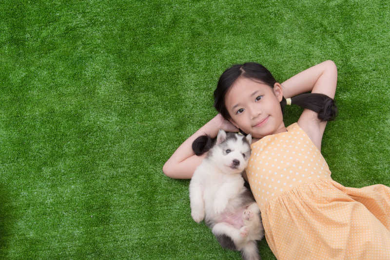 可爱的小女孩和她的小狗躺在草地上