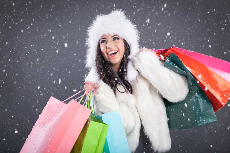 下雪的圣诞节里拿着一堆购物袋的性感美丽的女人