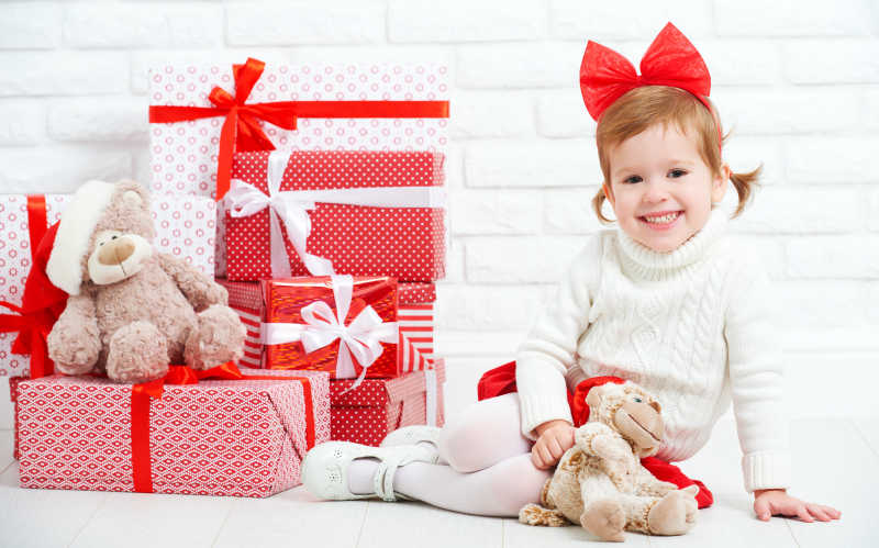 快乐小女孩和白墙边上的圣诞礼物