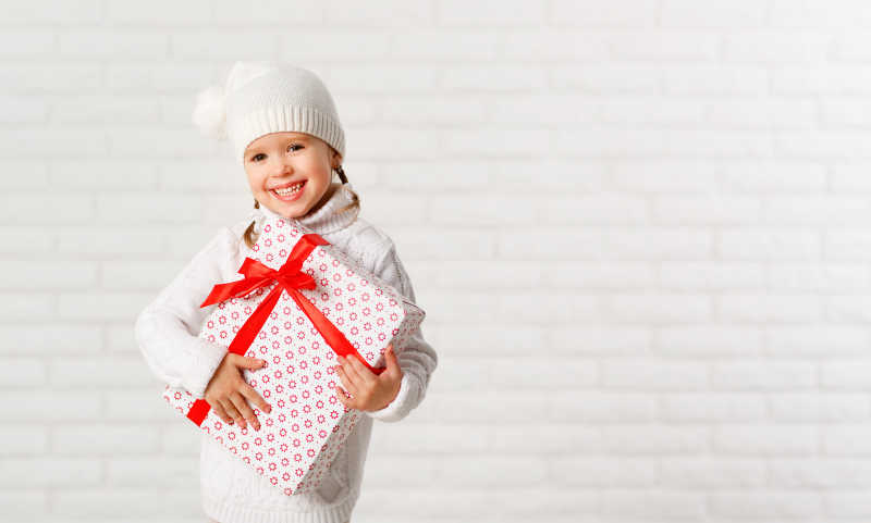 抱着圣诞礼物的快乐小女孩