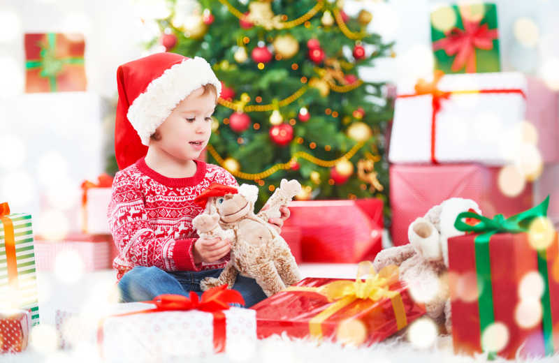 圣诞树旁边有圣诞礼物和快乐孩子