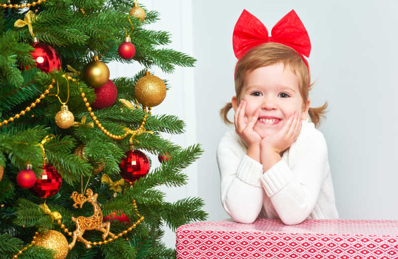 圣诞树旁有圣诞礼物和快乐小女孩
