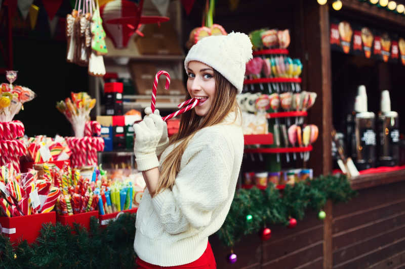一个面带笑容的年轻女子在啃圣诞糖果手杖