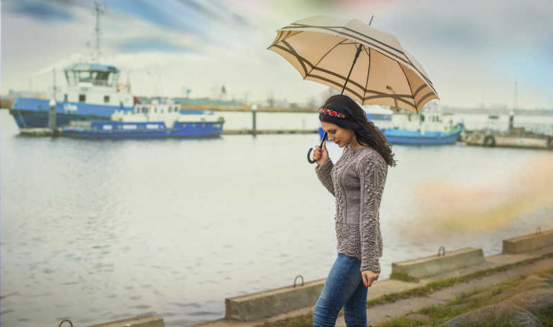 雨中在河边打着伞漫步的美女