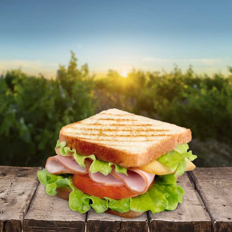 晴天户外阳光下木板上的夹肉三明治
