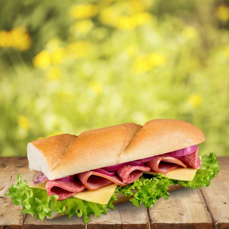 虚化黄色花背景下的木板上的夹肉三明治
