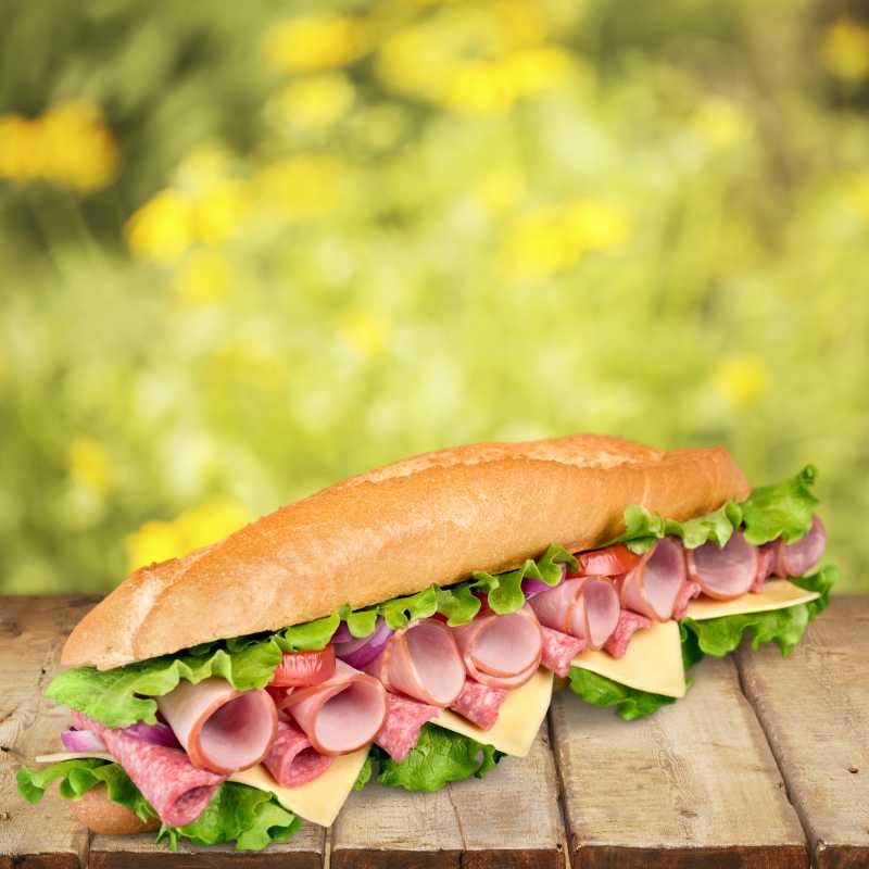 黄色户外背景下木板上的夹肉三明治