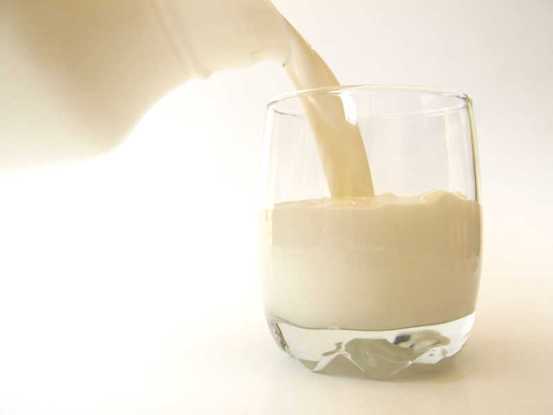 白色背景下往玻璃杯里倒入牛奶