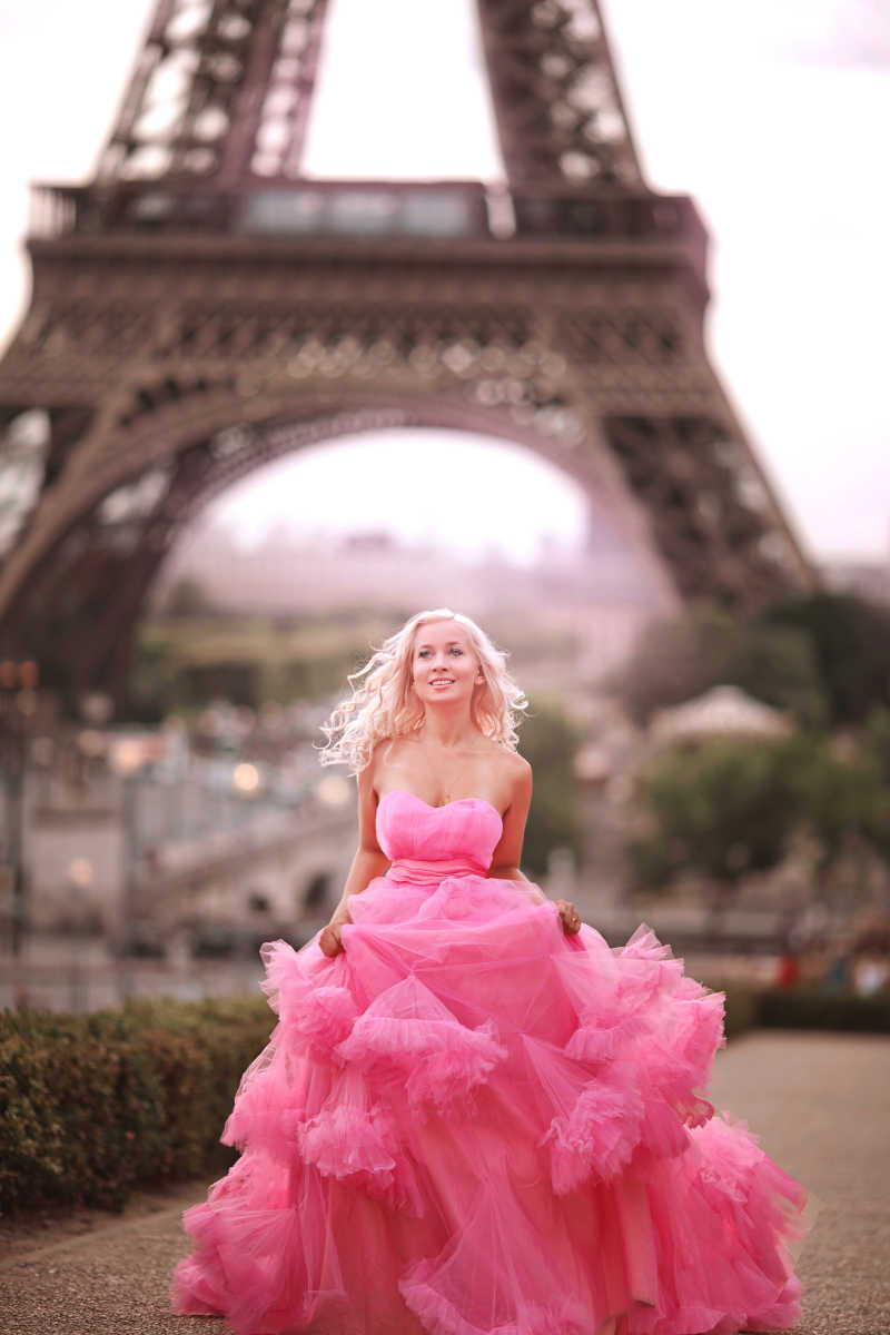 艾菲尔铁塔的背景上一个穿着粉红色连衣裙的漂亮女孩在奔跑