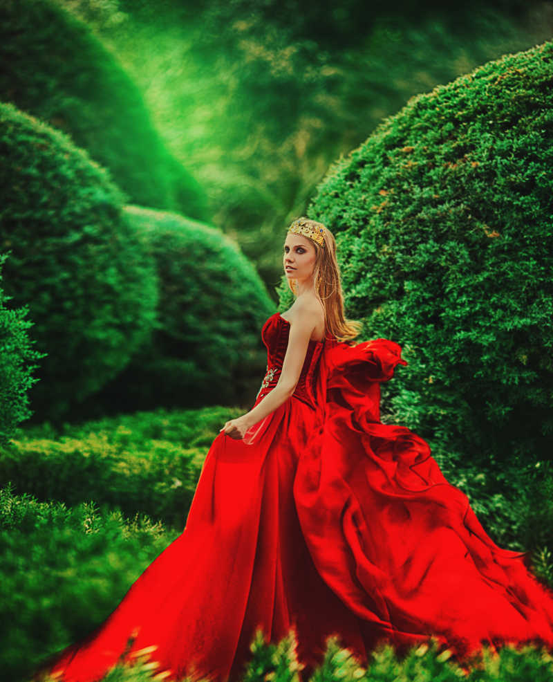 穿红色衣服的美女走在绿色的花园里
