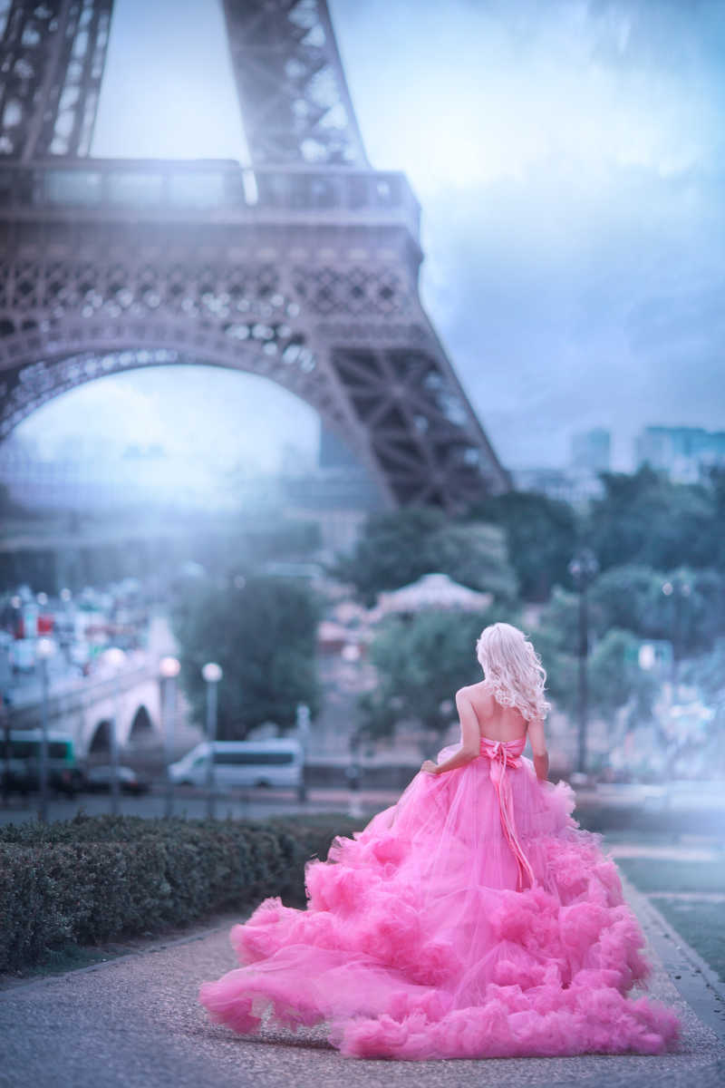艾菲尔铁塔背景下奔跑的穿粉红连衣裙的女孩