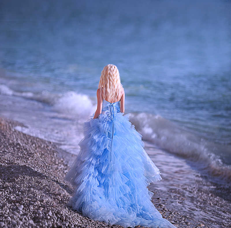 穿蓝色连衣裙的新娘走在海边