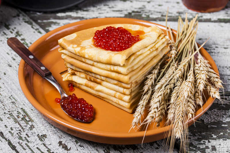 鱼子酱煎饼传统俄式餐桌上的木制背景