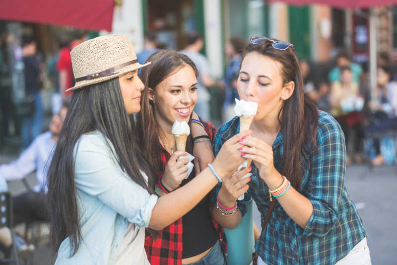 三个在城市里吃冰淇淋快乐的女孩