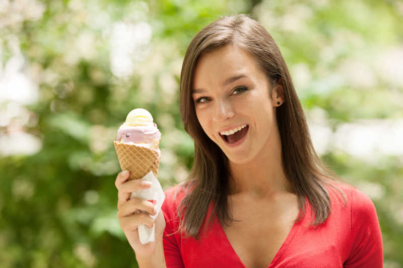 在公园里吃甜冰淇淋的年轻女孩