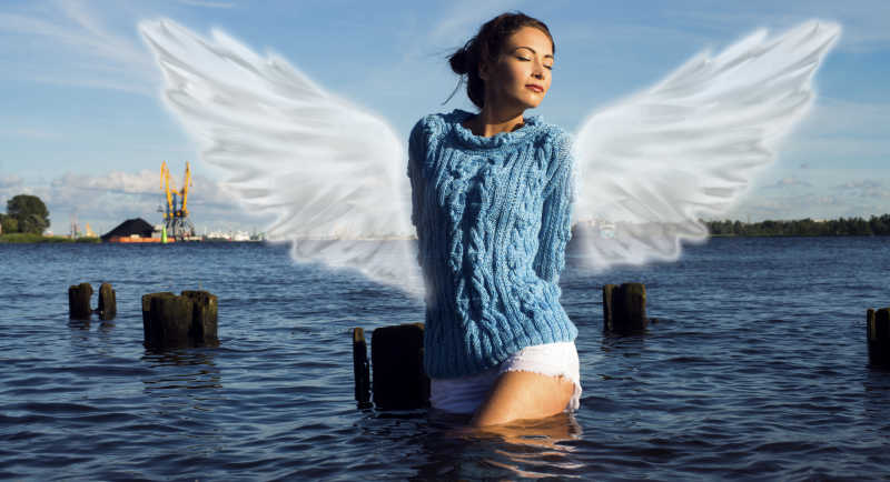 站在水中有着天使翅膀的女孩