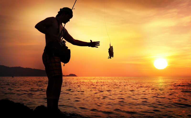 黄昏在湖边钓鱼的男人剪影