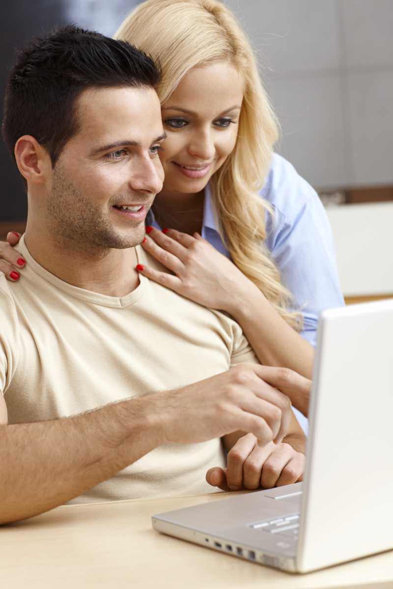 面带微笑的年轻夫妇在家里使用笔记本电脑
