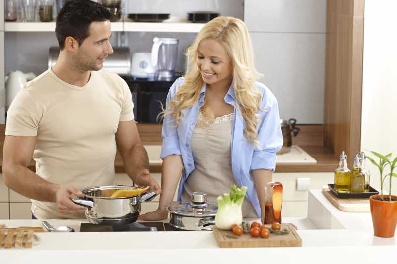 年轻的夫妇站在厨房里做饭