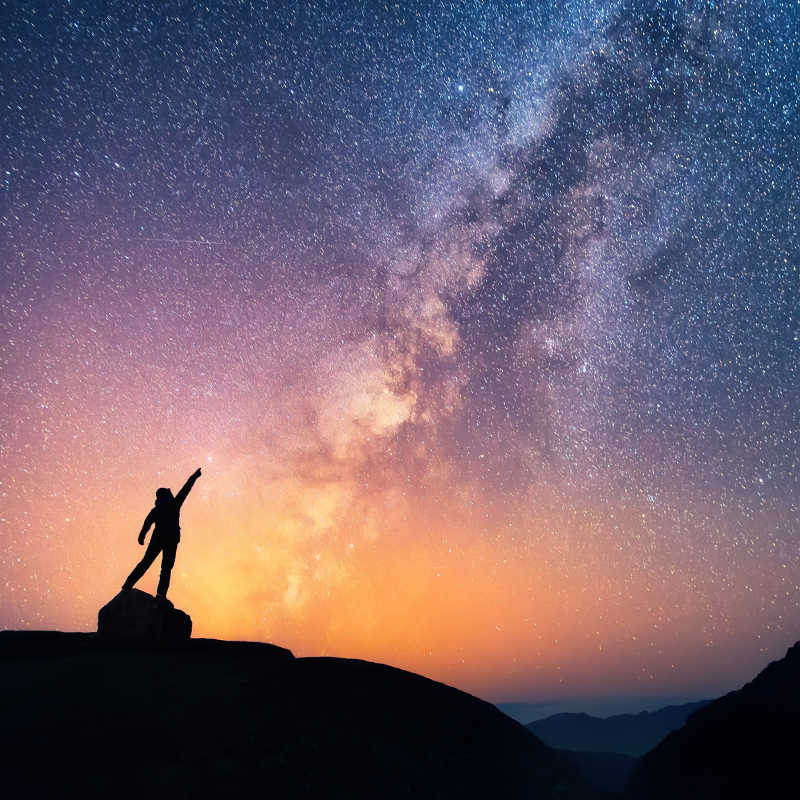 一个人站在山上指向夜空