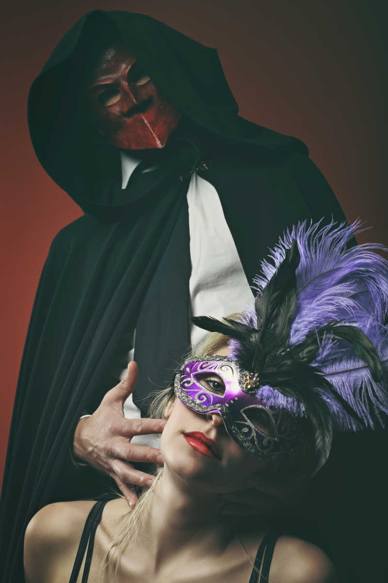 红色背景下带着面具的神秘夫妇