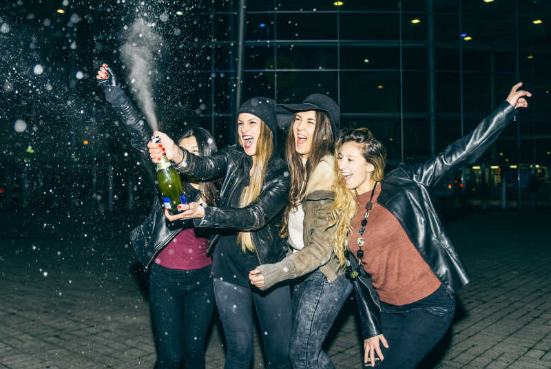在户外开香槟庆祝的四个年轻女孩