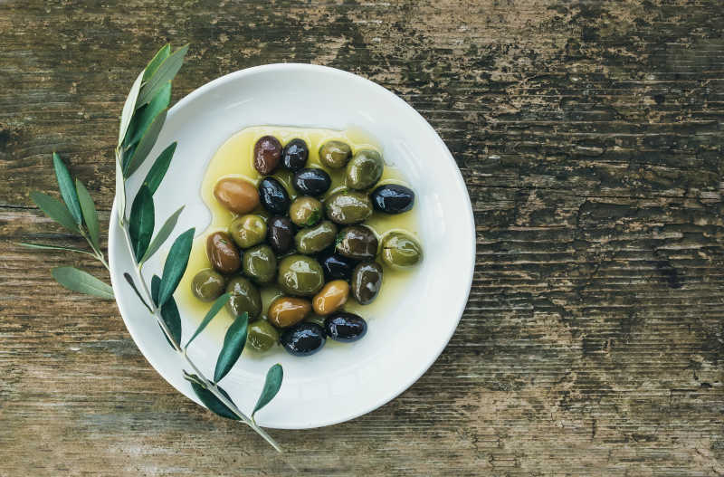 木桌上盘中橄榄油泡着的橄榄