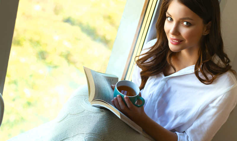 坐在窗边捧着咖啡和书的美女