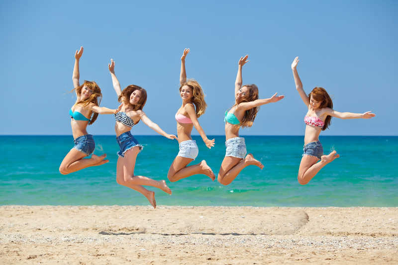 海滩上放松跳跃的女孩们