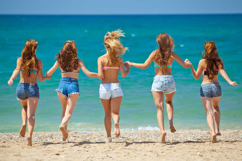 海滩上手拉手奔跑的女孩们