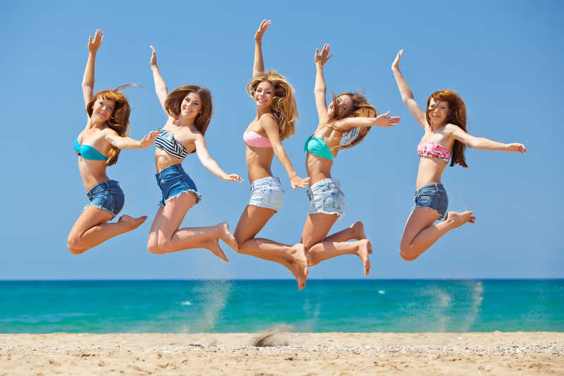 在海滩上跳跃放松的年轻女孩们