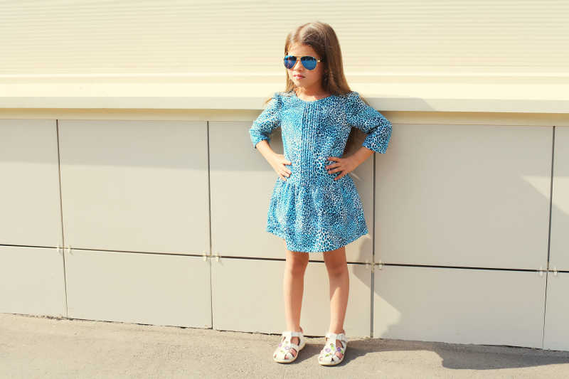 穿着蓝色连衣裙和戴着太阳镜的小女孩